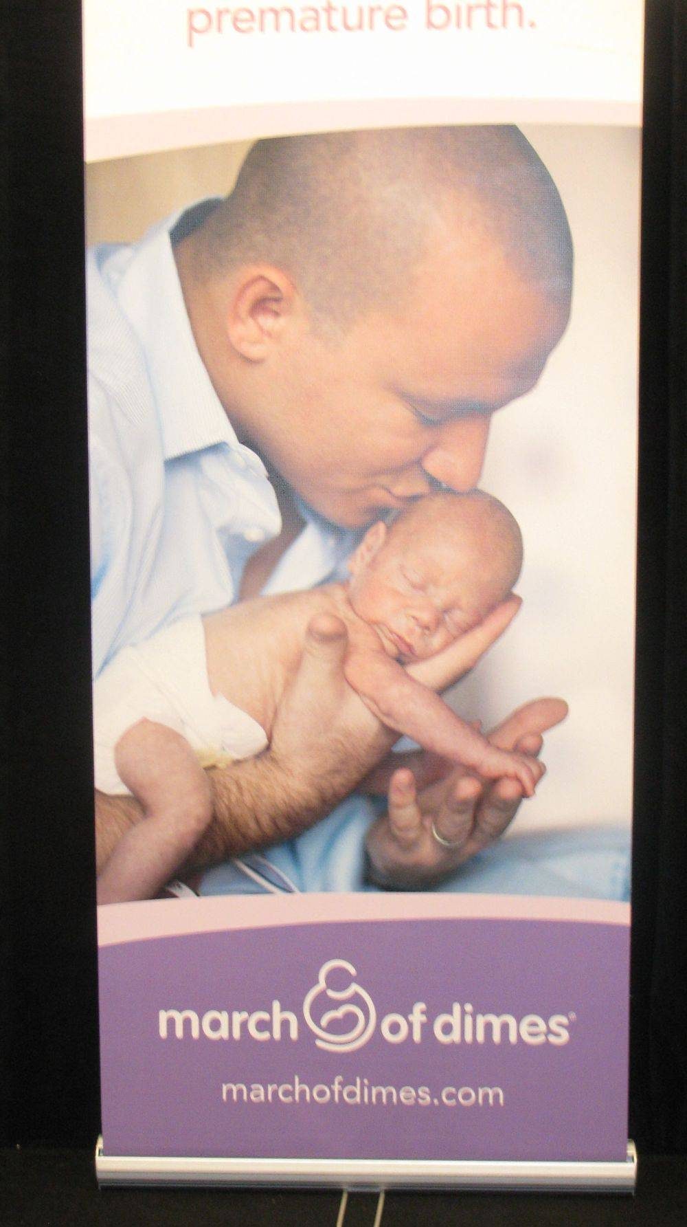 A newborn's hand holding an adult finger