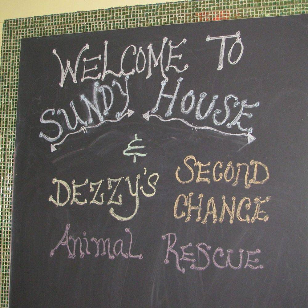 A chalkboard welcoming guests to Sundy House and Dezzy's Second Chance Animal Rescue